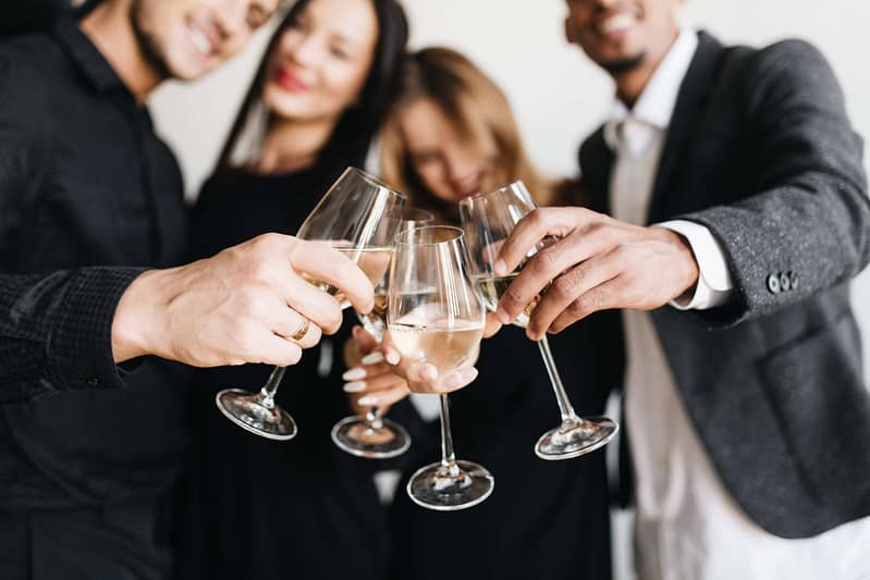 Indoor portrait of romantic blonde girl chilling at friend's party and posing with glass full of champagne. Relaxed young people in stylish outfit drinking wine during meeting and joking.. - Chorcha Entertainment Organización de eventos de San Valentín